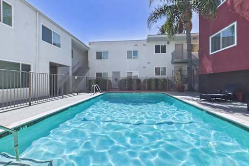 A swimming pool in front of a white and red building.