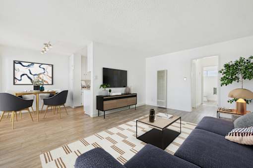 A living room with a black sofa and a wooden floor.