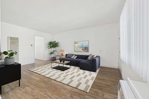 A living room with a blue couch and a painting on the wall.