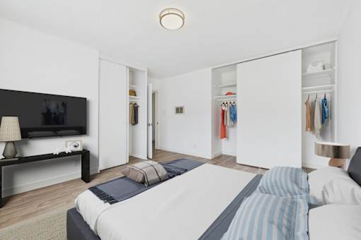 A bedroom with a bed, a television, and a clothing rack.