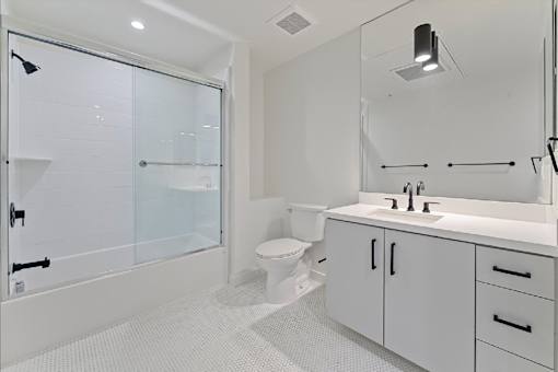 A white bathroom with a walk in shower and a toilet.