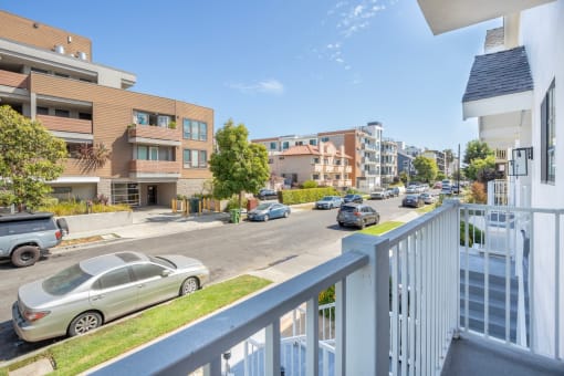 a view of a street from a balcony with cars parked on it