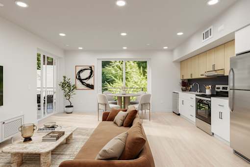 A modern living room with a brown sofa and a kitchen area in the background.