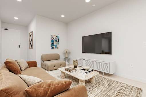 A living room with a brown couch, a white coffee table, and a flat screen TV mounted on the wall.
