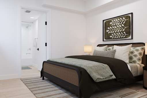 A bedroom with a bed, a lamp, and a painting on the wall.
