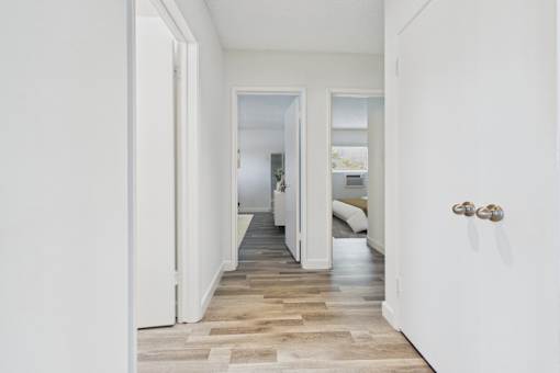 A hallway with a white door on the right and a white wall on the left.