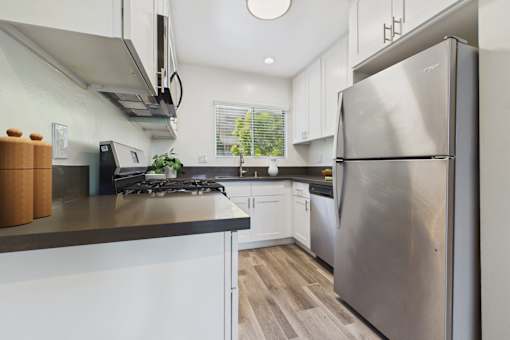 A modern kitchen with a stainless steel refrigerator and white cabinets.