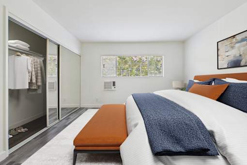 A bedroom with a bed, a bench, and a wardrobe.