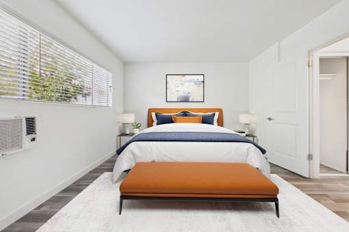 A bedroom with a bed, two lamps, and a window with blinds.