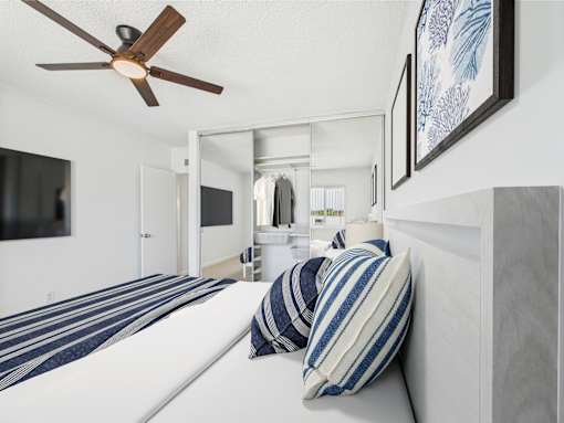A bedroom with a bed, pillows, and a ceiling fan.