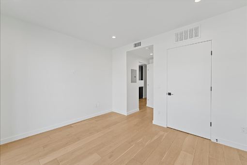 A white room with a wooden floor and a white door.
