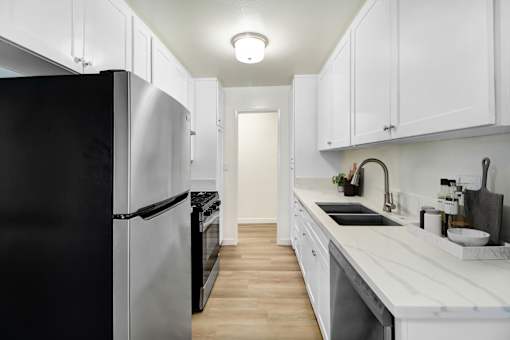 A kitchen with white cabinets and a black refrigerator.