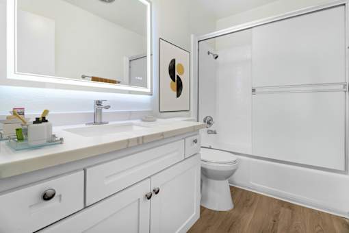 A white bathroom with a toilet, sink, and mirror.