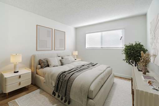 A bedroom with a large bed and a nightstand with a lamp.