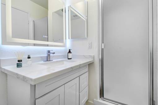 A white bathroom with a sink and mirror.