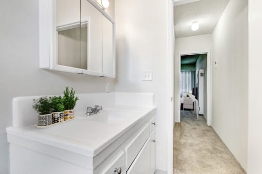 a bathroom with a sink and a mirror and a hallway to a bedroom