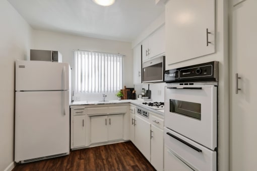 an empty kitchen with white appliances and white cabinets