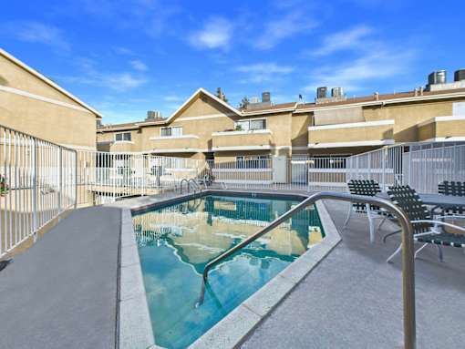 A small pool with a metal railing and chairs around it.