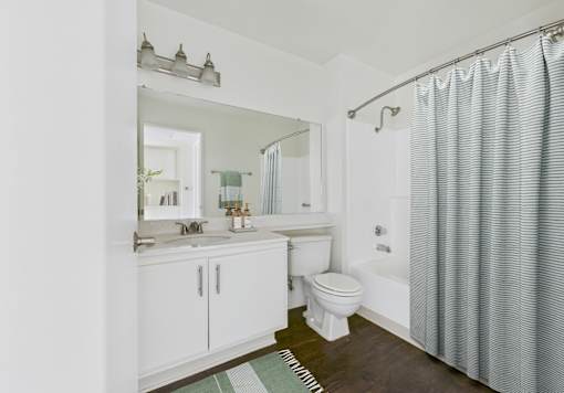 A white bathroom with a toilet, sink, and shower.