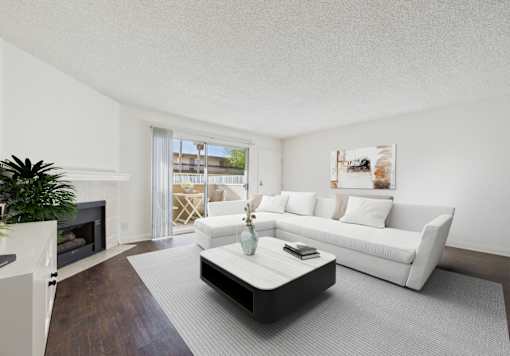 A living room with a white couch, a coffee table, and a fireplace.