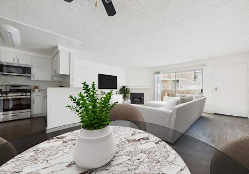 A plant in a white pot sits on a marble table in a modern kitchen and living room.