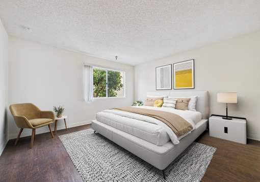 A bedroom with a large bed, a chair, and a lamp.