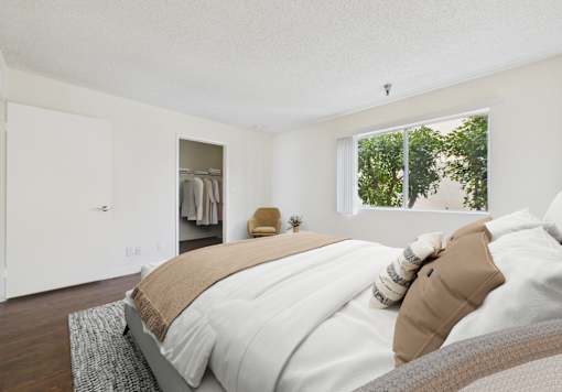 A bedroom with a large bed and a window overlooking trees.