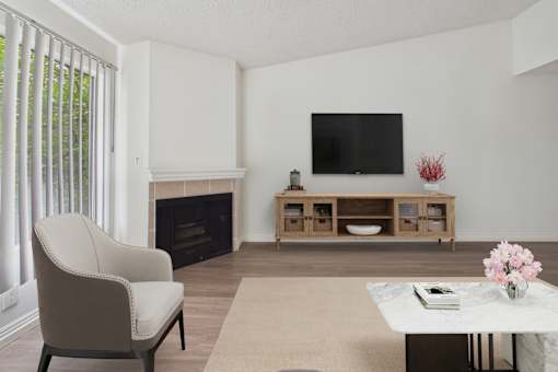A living room with a fireplace, a chair, a table, and a television.