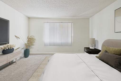A bedroom with a large bed and a television on the wall.