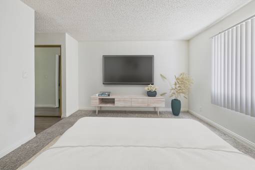A bedroom with a bed, a tv, and a bench.