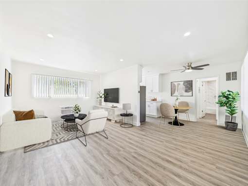 A living room with a white couch, a television, and a ceiling fan.