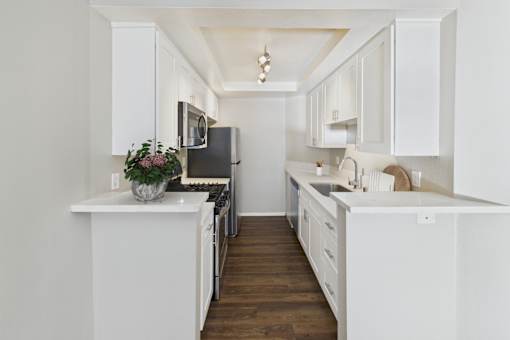 A kitchen with white cabinets and a black fridge.