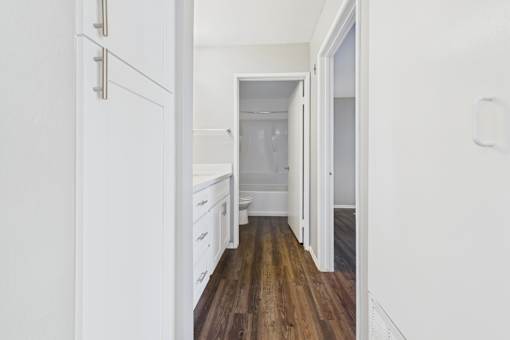 A white kitchen with wooden floors and white cabinets.