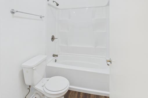 A white toilet sits next to a white bathtub in a bathroom.