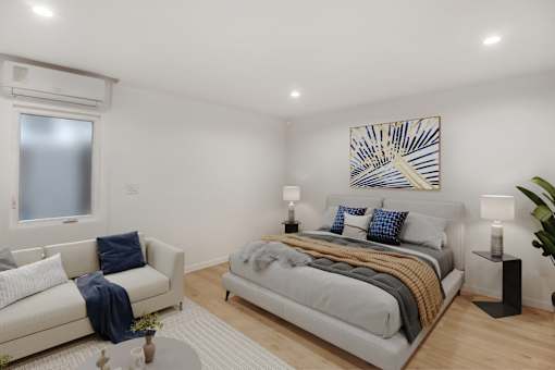 A bedroom with a bed, a couch, and a painting on the wall.