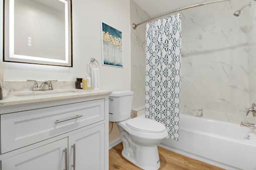 A white toilet sits in a bathroom with a patterned shower curtain.