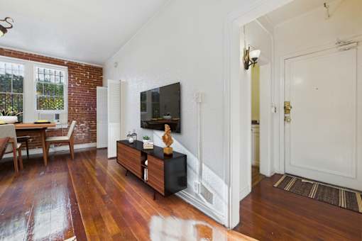 A living room with a wooden floor and a television on a cabinet.