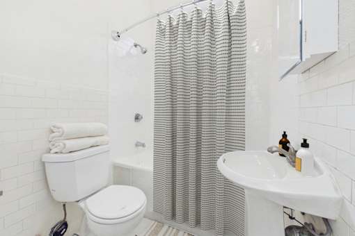 A white bathroom with a toilet, sink, and shower curtain.