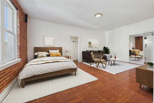 A bedroom with a bed, a chair, and a plant.
