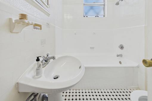 A white bathroom sink with a white tiled wall.