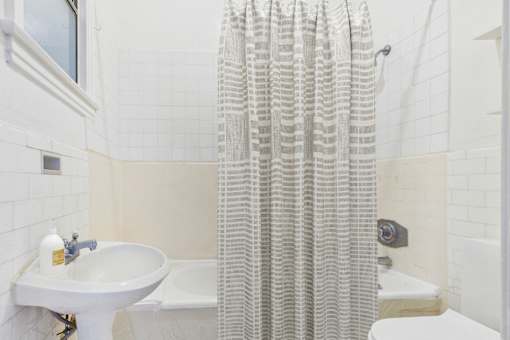 A white bathroom with a shower curtain and a white sink.