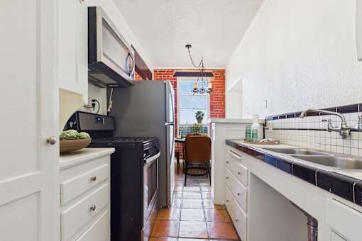 A kitchen with a black fridge and white cabinets.