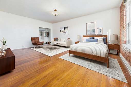 A bedroom with a large bed and a wooden floor.