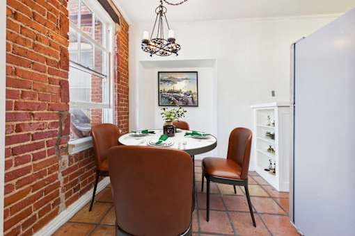 A dining room with a table set for two and a chandelier hanging from the ceiling.