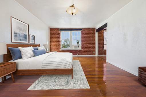 A bedroom with a bed, nightstand, and window.