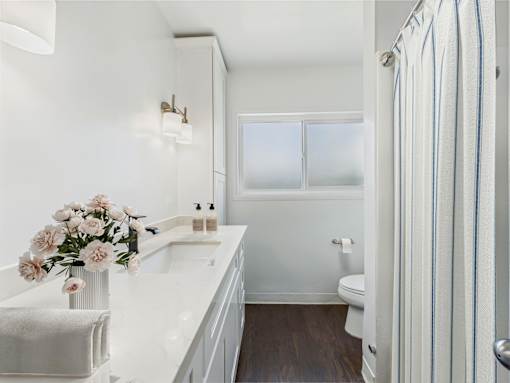 A white bathroom with a toilet, sink, and striped shower curtain.