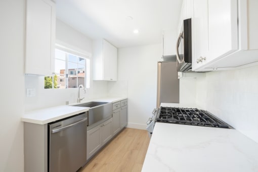 a renovated kitchen with white cabinets and stainless steel appliances