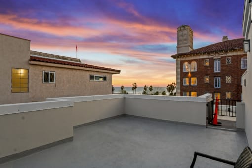 the view of the sunset from the balcony of a house with a roof