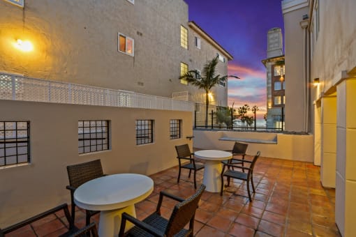 a patio with tables and chairs and a sunset in the background
