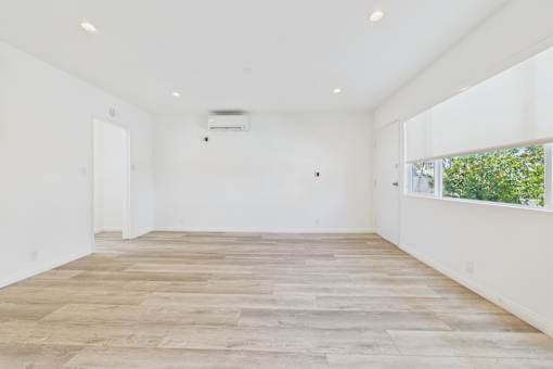 A spacious room with wooden flooring and white walls.
